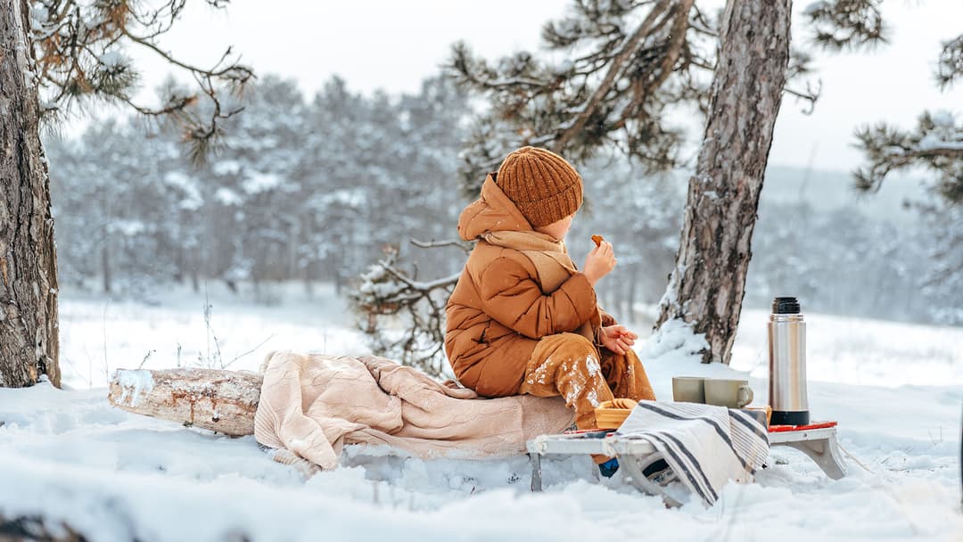 Poika picnicillä talvisessa maisemassa talvileikkien lomassa