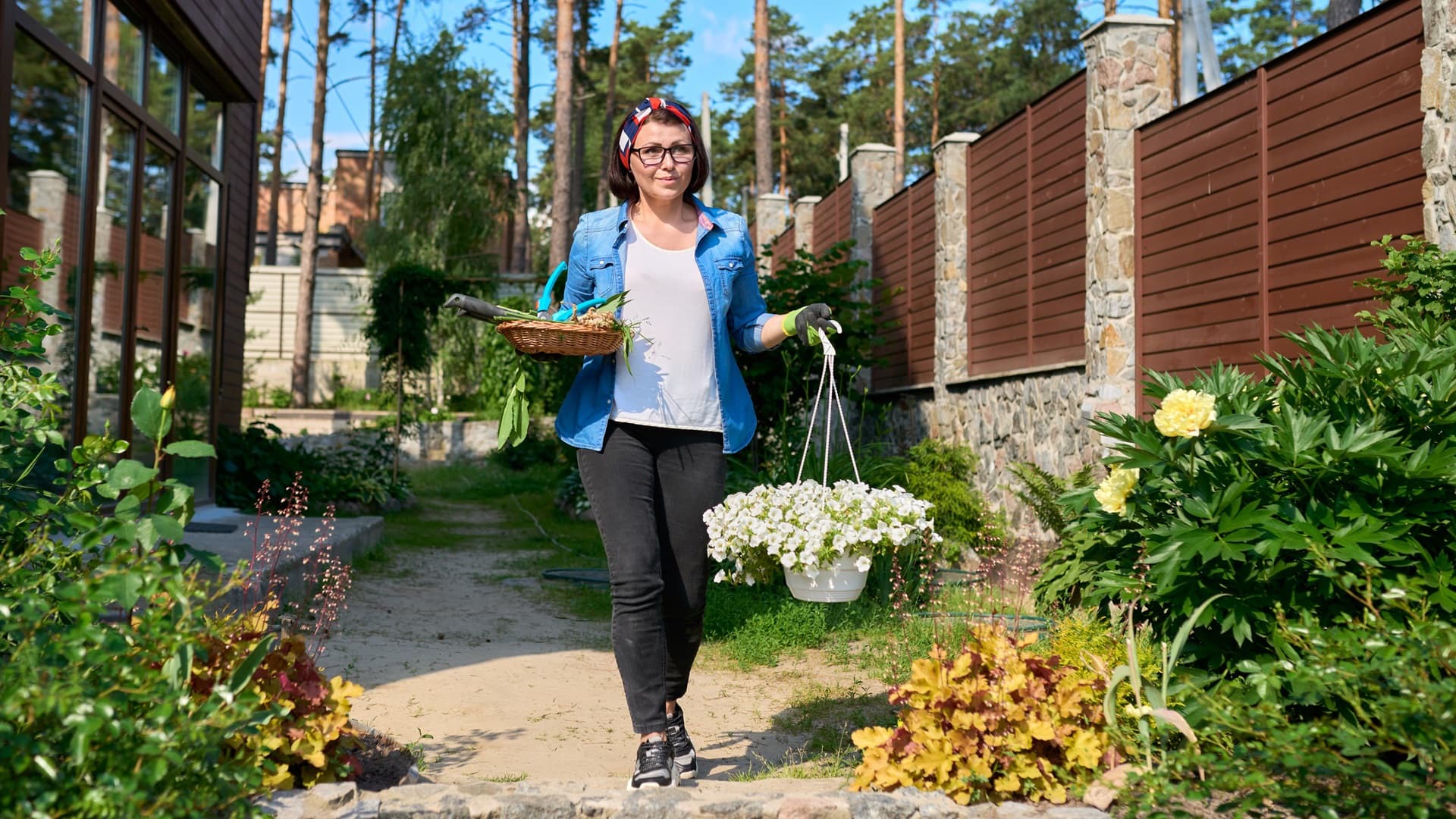 nainen kävelee puutarhassa kukkien kanssa